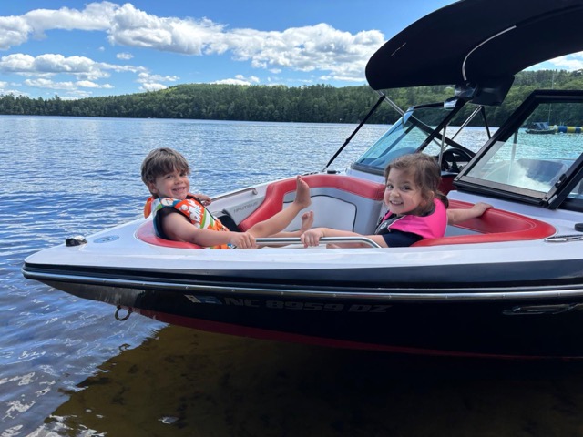 Two Little Loons smiling in life jackets aboard a Wigwam ski boat on the lake
