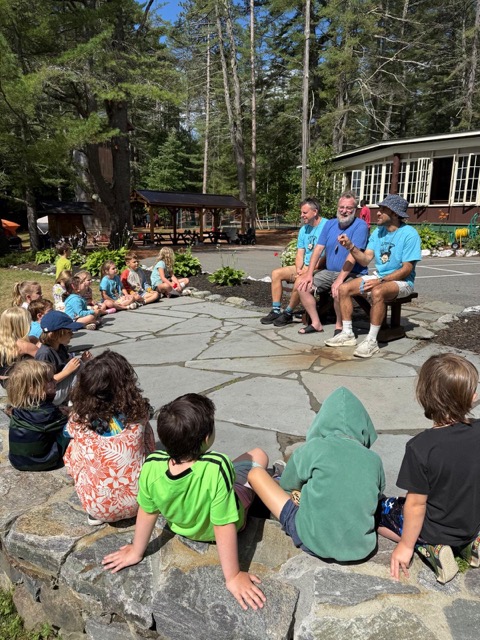 Little Loons campers and counselors sitting in a circle on the flagstone patio