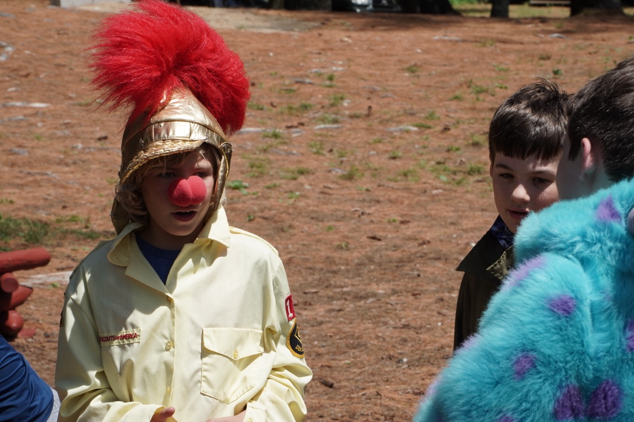 Camper in a Roman helmet, red wig, and clown nose during a costume-themed camp event