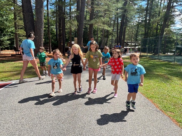 Little Loons walking hand-in-hand down a camp path with their counselor